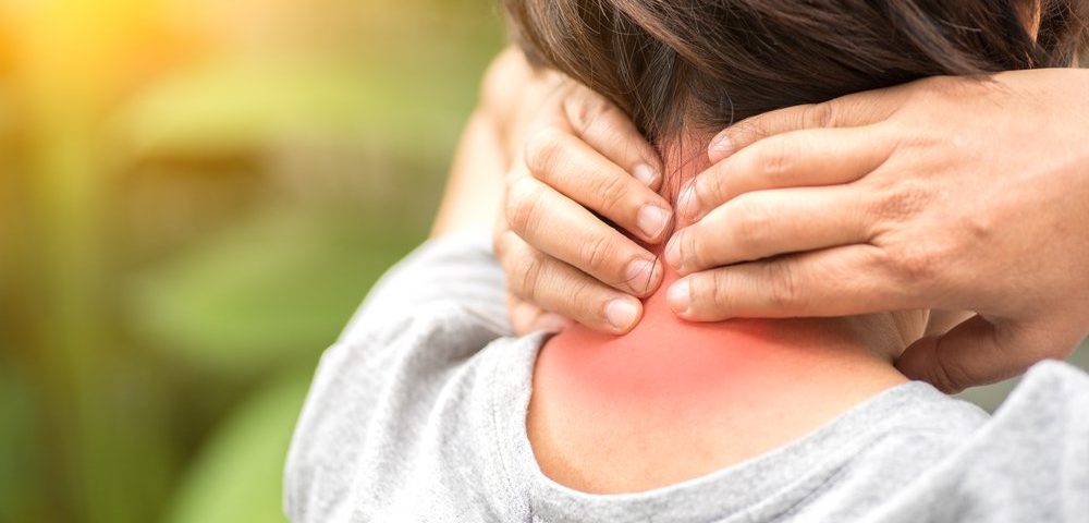 Person with neck pain massaging back of neck that appears red and inflamed.